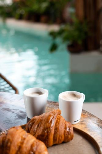 a table with two cups of coffee and a croissant at Xkeban Tulum Adults Only in Tulum