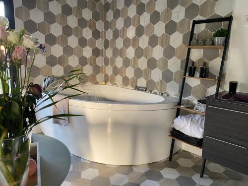 baño con bañera blanca y pared en Chambre chaleureuse avec jacuzzi, en Le Mesnil-en-Vallée