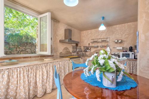 a kitchen with a table with a vase of flowers on it at Lu Casal de Fiò in Alghero