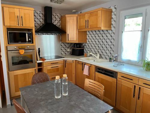 une cuisine avec des armoires en bois et une table avec des chaises dans l'établissement Les Pléiades, à Noisy-le-Grand