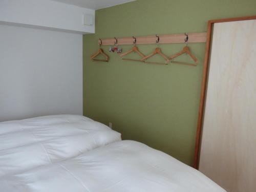 - une chambre avec un lit et un mur vert avec des cintres dans l'établissement Kyoto City - Hotel - Vacation STAY 88891v, à Kyoto