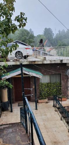 a dog standing on a deck with a car on a balcony at Cozy Cottage at Afgan Lodge in Murree