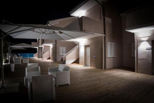 a room with white chairs and tables and umbrellas at Balconi Del Conero in Numana