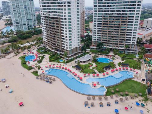 an aerial view of the pool and beach at a resort at Ocean Front Condo Sleeps 4 Adults-Grand Venetian T3000-1606 in Puerto Vallarta