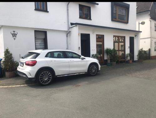 a white car parked in front of a white house at Seven’S Apartments in Löhnberg