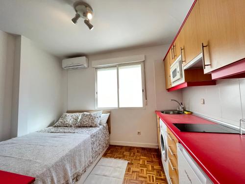 a small kitchen with a bed and a red counter top at Piso Augusto Acogedor 5 in Madrid