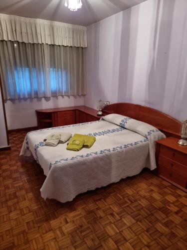 a bedroom with a bed with two yellow towels on it at Alojamiento bueu centro in Bueu