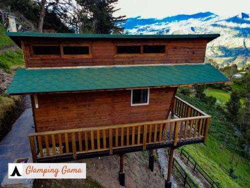 a log cabin with a green roof on a balcony at Glamping la Kumbre - Gama in Gama