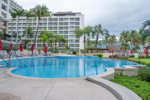 a swimming pool with a large building in the background at Ocean Front Condo Sleeps 4 Adults-Grand Venetian T3000-1606 in Puerto Vallarta