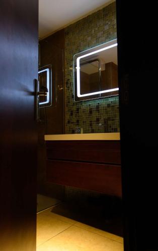 a bathroom door with a sink and a mirror at Best Western Plus Soaho Douala Airport in Douala