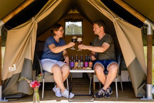 a man and a woman sitting at a table in a tent at Charmecamping & Appartementen De Regge-Vallei in Den Ham