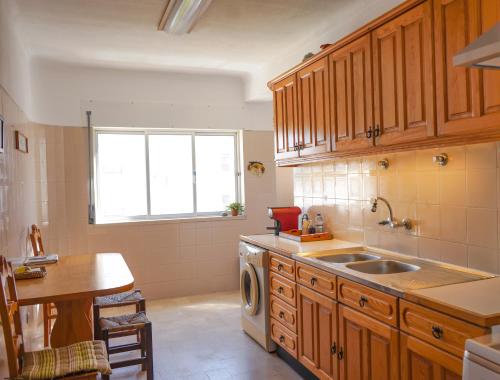 a kitchen with wooden cabinets and a sink and a window at Gustavo's Place in Sines