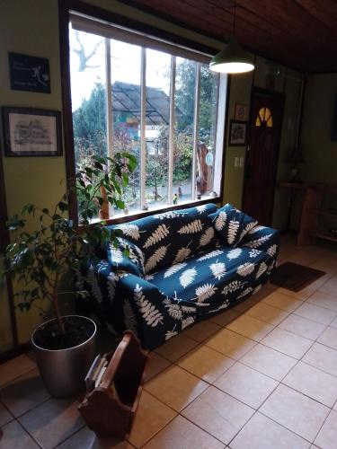 a couch in a living room with a large window at Cabaña la Solar. in Frutillar