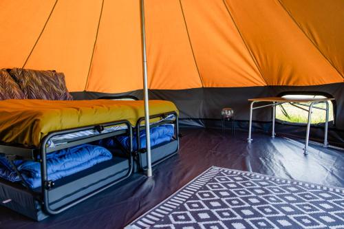 an orange tent with a bed and a chair in it at Charmecamping & Appartementen De Regge-Vallei in Den Ham