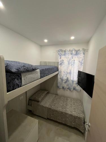 a bedroom with two bunk beds and a flat screen tv at La Ginestra in Giardini Naxos