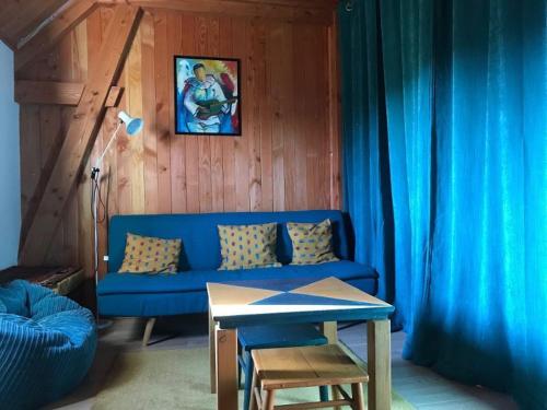 a living room with a blue couch and a table at Gîte familial restauré en pleine nature avec terrasse, proche forêt, idéal pour groupes et PMR - FR-1-410-255 in Chemiré-en-Charnie