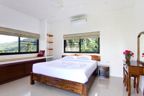 a bedroom with a bed and a desk and windows at 2 Bays Villa in Thong Nai Pan Yai
