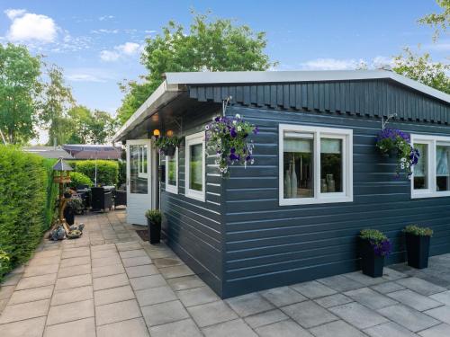 a blue tiny house with white windows and flowers at Lovely Wooden Chalet with garden in Reutum in Reutum