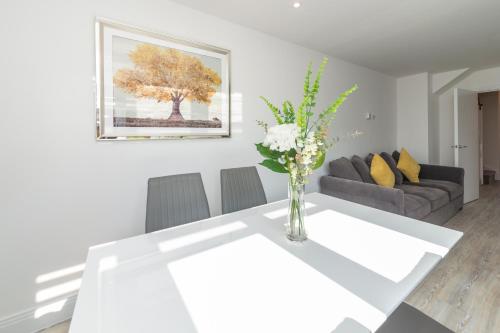 a living room with a white table with a vase of flowers at Greenfield Holiday Homes in Bracknell