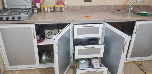 un bancone della cucina con cassetti bianchi e lavandino di Superbe Appartement ad Al-Ḥoseyma