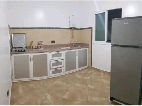 a small kitchen with a refrigerator and a sink at Superbe Appartement in Al Hoceïma