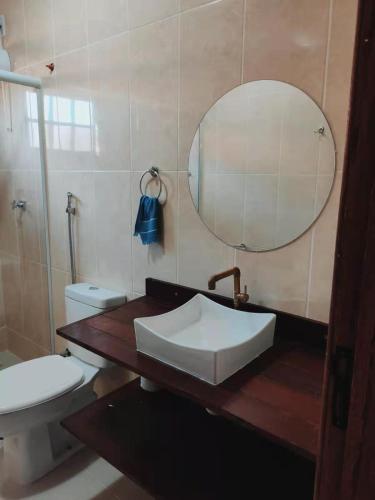 a bathroom with a sink and a toilet and a mirror at Pousada Blues in Ipiabas