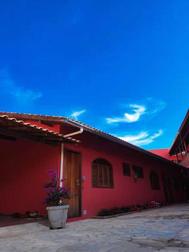 a red building with a potted plant in front of it at Pousada Blues in Ipiabas