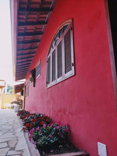 a red building with a window and some flowers at Pousada Blues in Ipiabas