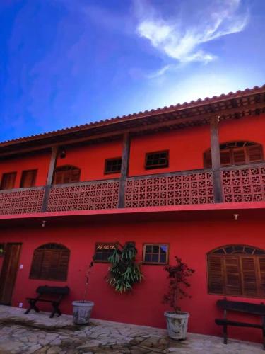 a red building with a balcony on the side of it at Pousada Blues in Ipiabas