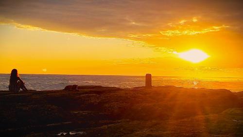 a person sitting on the beach watching the sunset at RocaSol Casa d´Mar in El Zonte