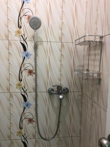 a shower in a bathroom with flowers on the wall at Shaima Homestay Syari'ah in Bukittinggi