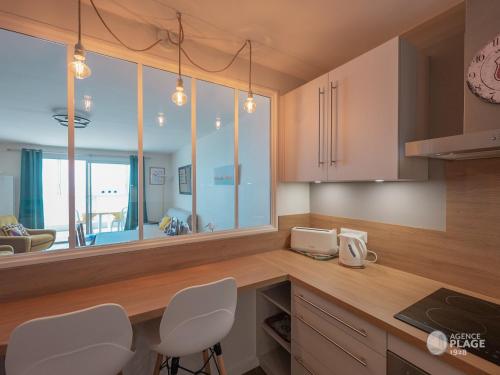 - une cuisine avec des chaises blanches et un comptoir dans l'établissement Appartement 66m² rénové, 1 chambre, vue mer, 4ème étage, fibre, 3 étoiles - FR-1-197-198, à Les Sables-dʼOlonne