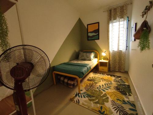 a small room with a bed and a fan at Mini Green Homestay in Kulai