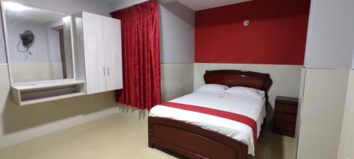 1 dormitorio con cama y pared roja en Hotel Real Bolivar, en Chimbote