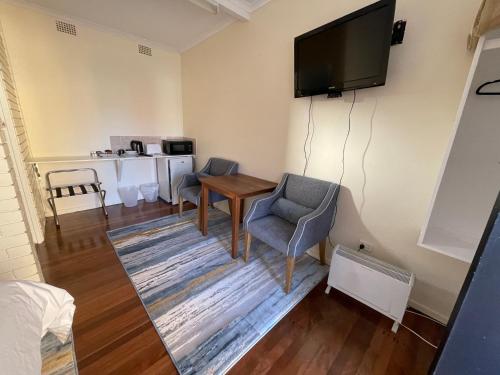 a living room filled with furniture and a tv at Railway Motel Dorrigo Commercial Hotel in Dorrigo