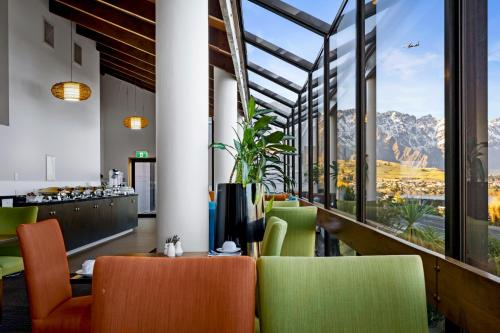 a restaurant with a view of the mountains through the windows at Copthorne Hotel & Apartments Queenstown Lakeview in Queenstown