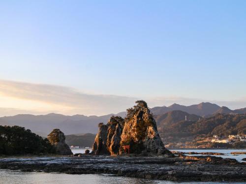 a rock formation in the water with mountains in the background at WhyKumano in Nachikatsuura