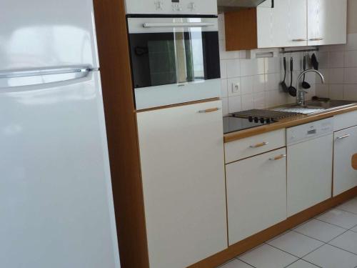 une cuisine avec des armoires blanches et un réfrigérateur blanc dans l'établissement Magnifique Appartement Face Mer avec 2 Balcons, Terrasse et Ascenseur - FR-1-672-4, à Merlimont