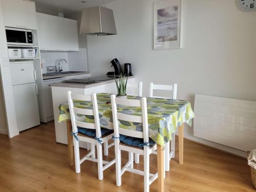 une cuisine avec une table et quatre chaises et un comptoir de cuisine dans l'établissement Appartement cosy face mer avec balcon et parking privé - FR-1-672-13, à Merlimont