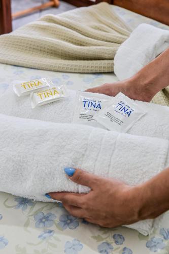 a person holding a pile of towels on a bed at Pousada da Tina in Ubatuba