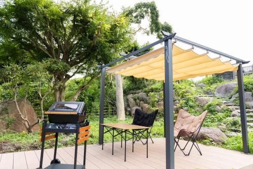 a patio with a grill and a table and chairs at Resort stay Bowen ~伊豆高原~ in Futo