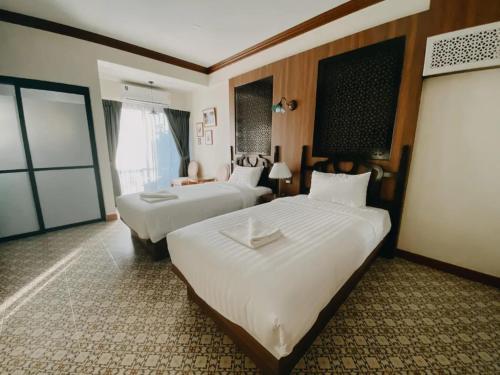 a hotel room with two beds and a window at Baan Chao Khun Hotel in Ban Khlong Lat Bua Khao