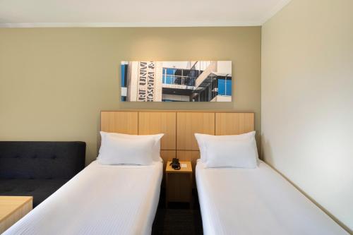 a room with two beds and a couch at Mercure Sydney Macquarie Park in Sydney