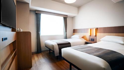 a hotel room with two beds and a flat screen tv at Hotel Monte Hermana Tokyo in Tokyo
