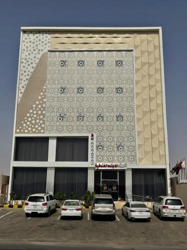 a building with cars parked in a parking lot at شهرزاد للأجنحة الفندقية in Abū Qa‘ar