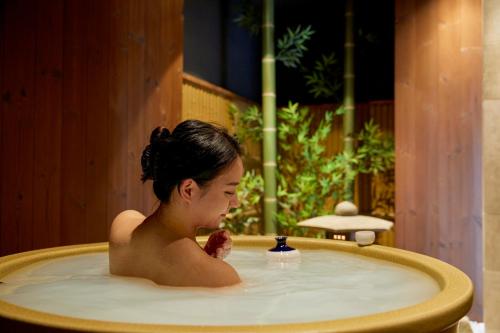 a woman in a jacuzzi bathtub at 古今 天下茶屋 with a private parking lot and a half open-air bath and direct to KIX in Osaka