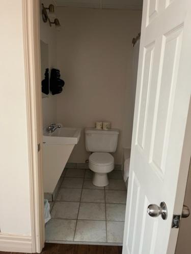 a white bathroom with a toilet and a sink at Hôtel Motel la MInganie in Longue-Pointe-de-Mingan