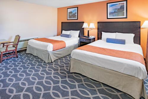 a hotel room with two beds and a desk at Howard Johnson by Wyndham Lenox in Lenox