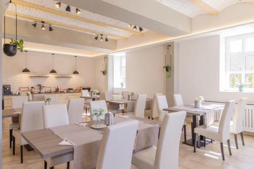 a dining room with tables and white chairs at Magtár Villa in Bóly