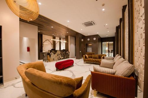 a large living room with couches and a red chair at Mastiff Hotel Ankleshwar in Ankleshwar